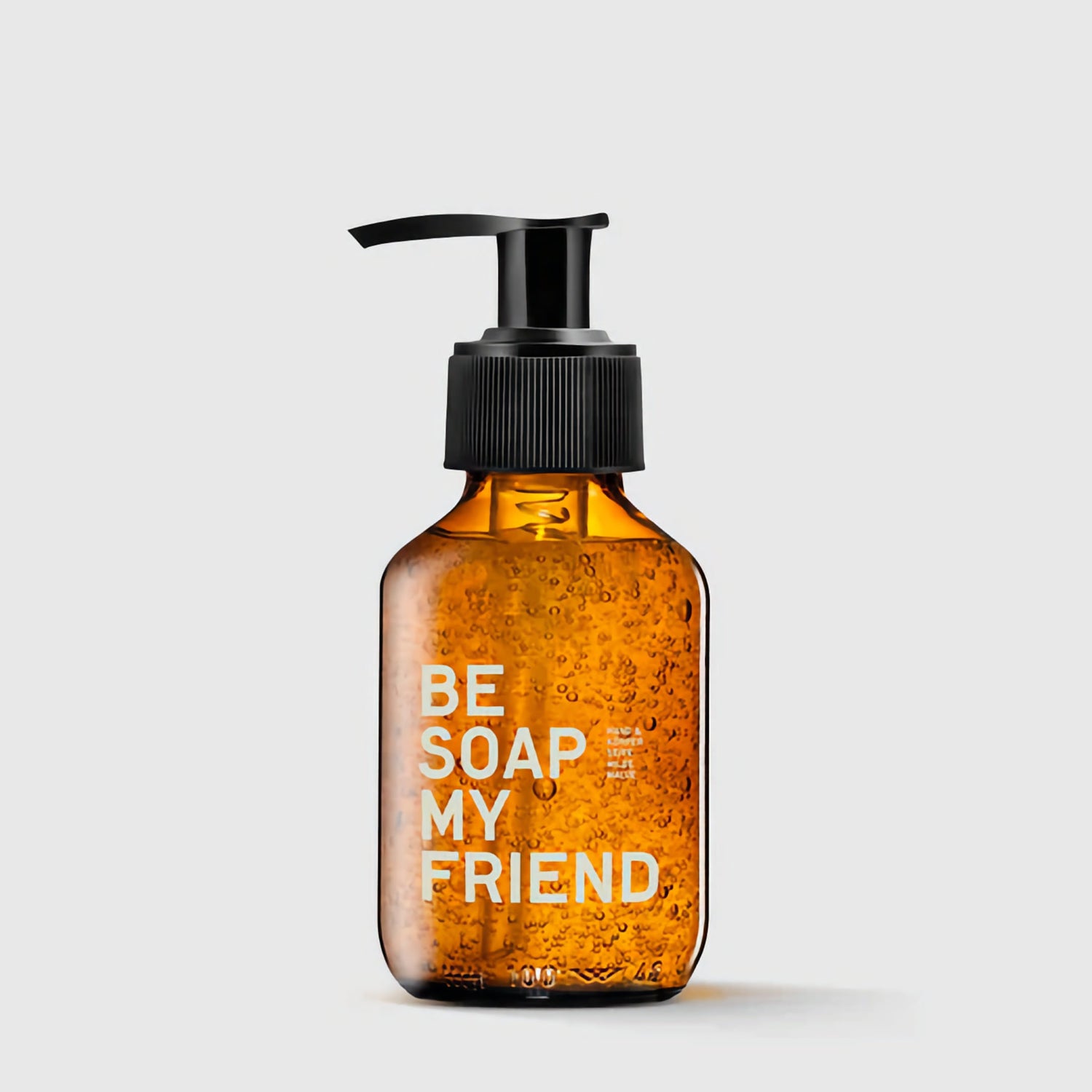 Amber pump bottle of hand and body soap with white "Be Soap My Friend" text and visible soap bubbles.