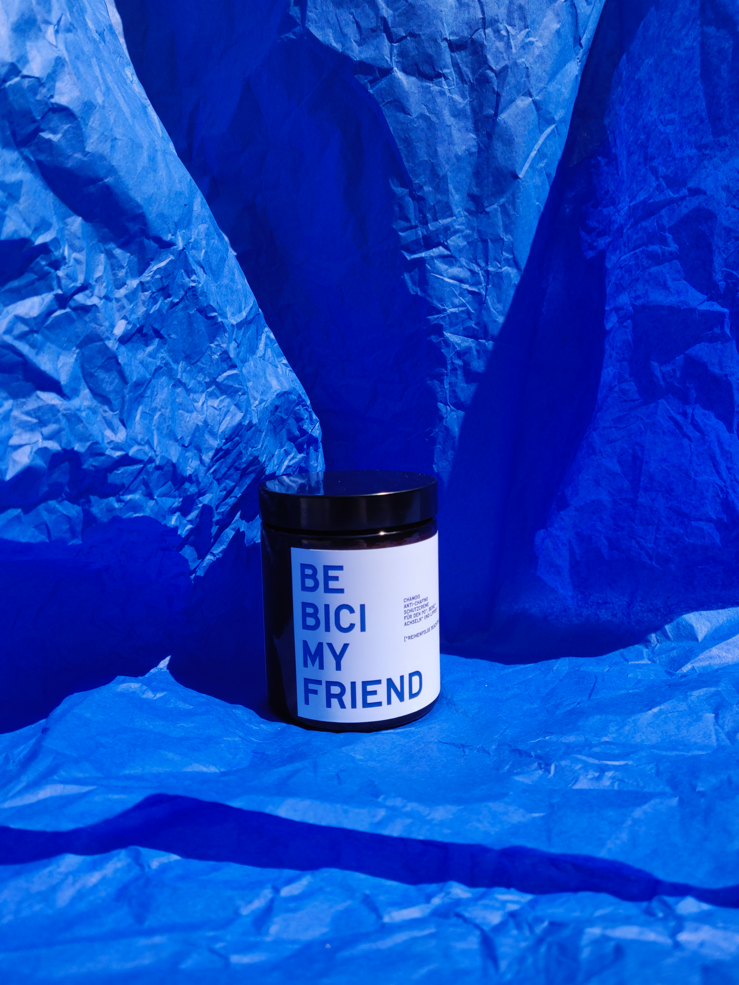 120ml white jar of Be Bicy My Friend chamois cream on crumpled blue paper background.