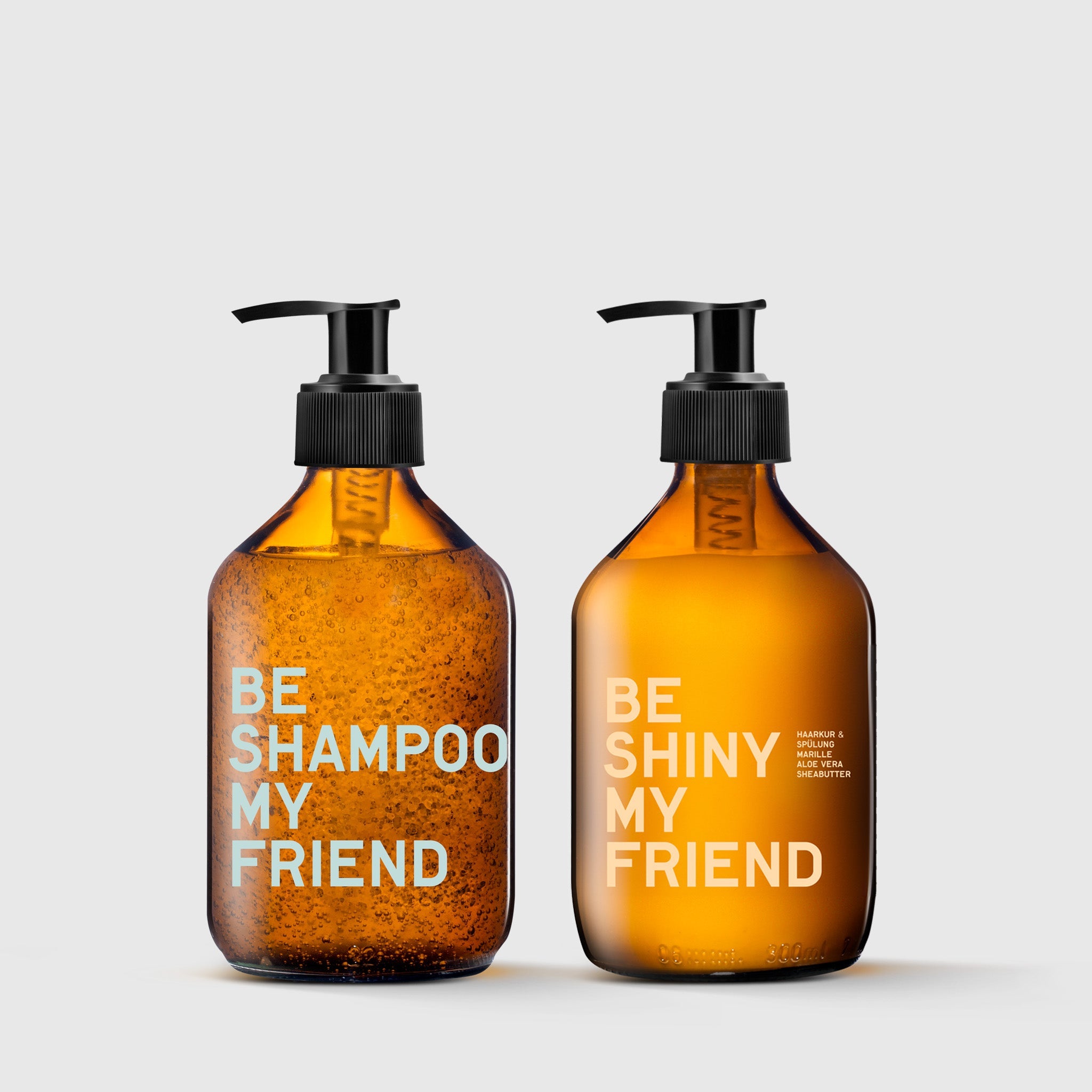 Amber glass pump bottles labeled "Be Shampoo My Friend" and "Be Shiny My Friend" on a gray background.
