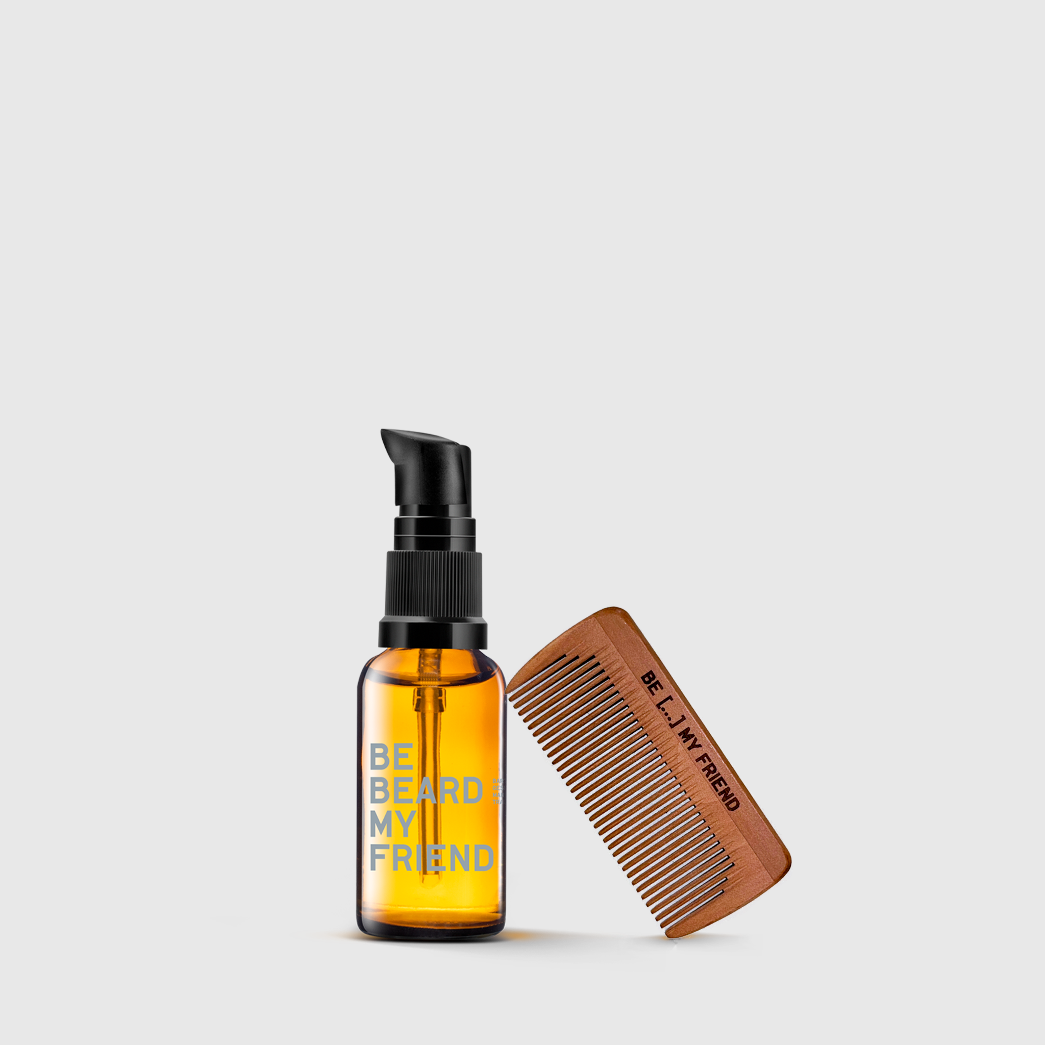 Amber glass bottle with black pump labeled "Beard My Friend" and small wooden beard comb with "BEARD" engraving.