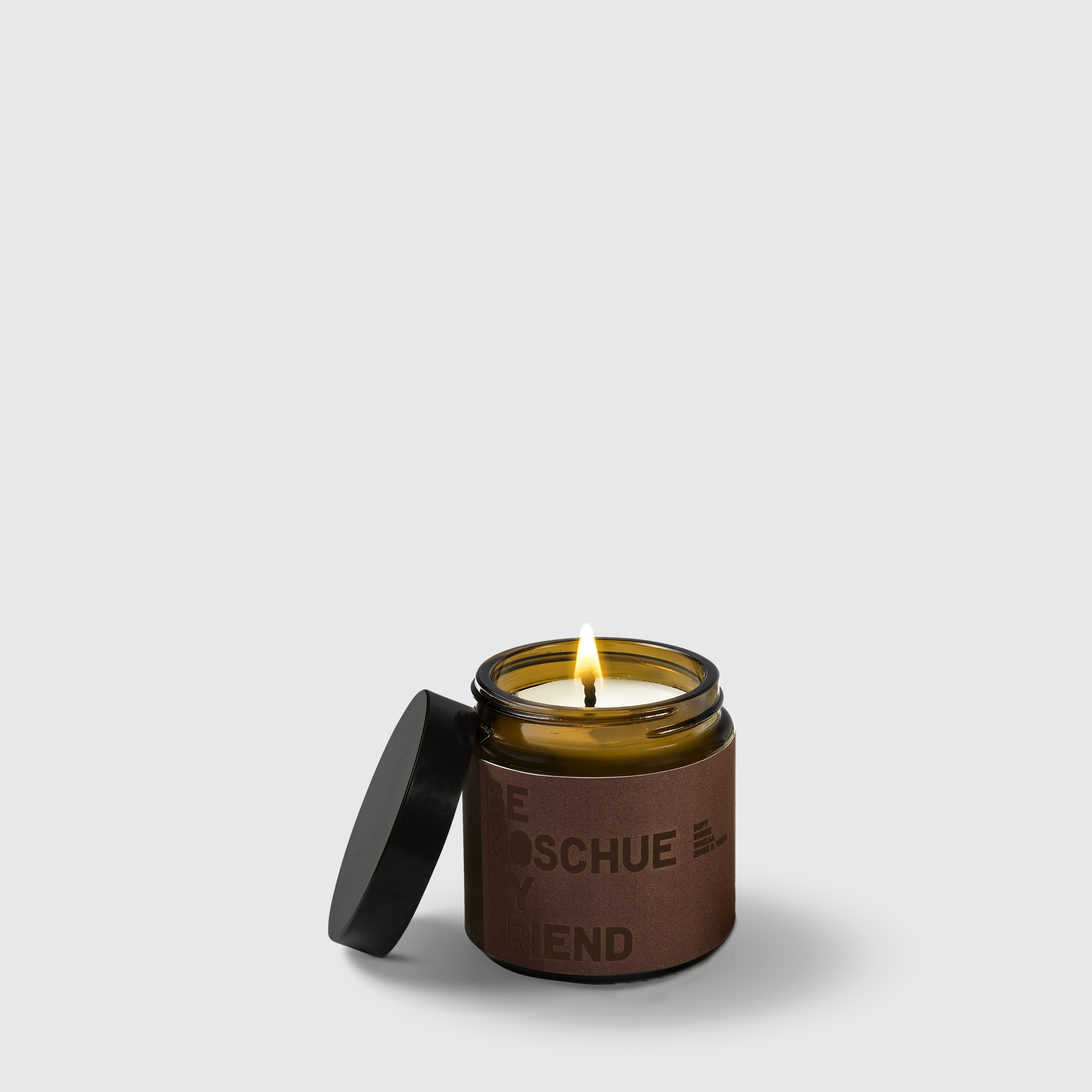 Brown glass vanilla scented candle with black lid and labeled brown band, lit wick.
