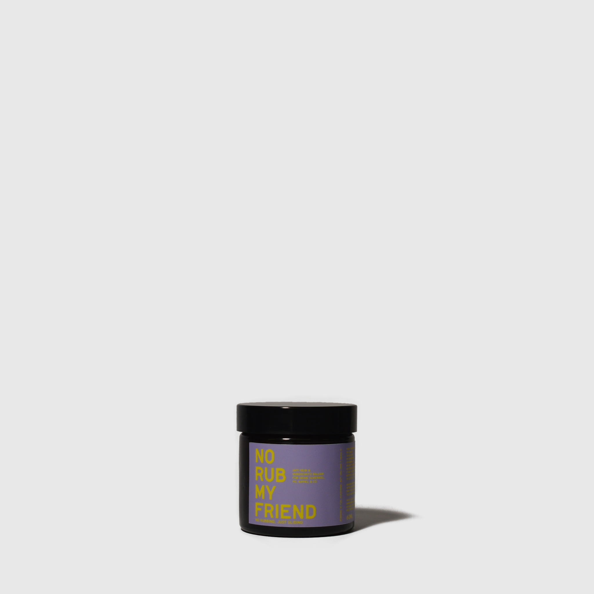 Small dark glass jar with black lid and purple label featuring yellow and green text.