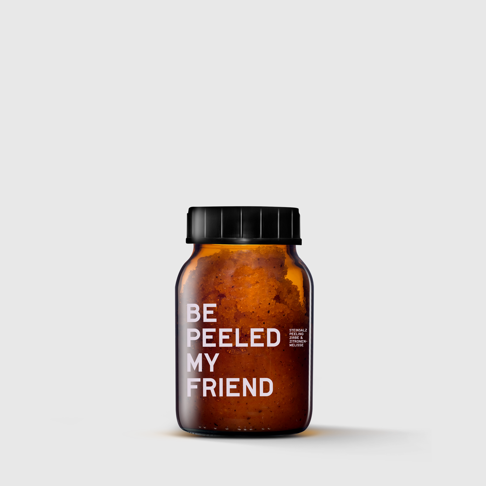 Amber glass jar with black lid containing brown body scrub labeled "Be Peeled My Friend".