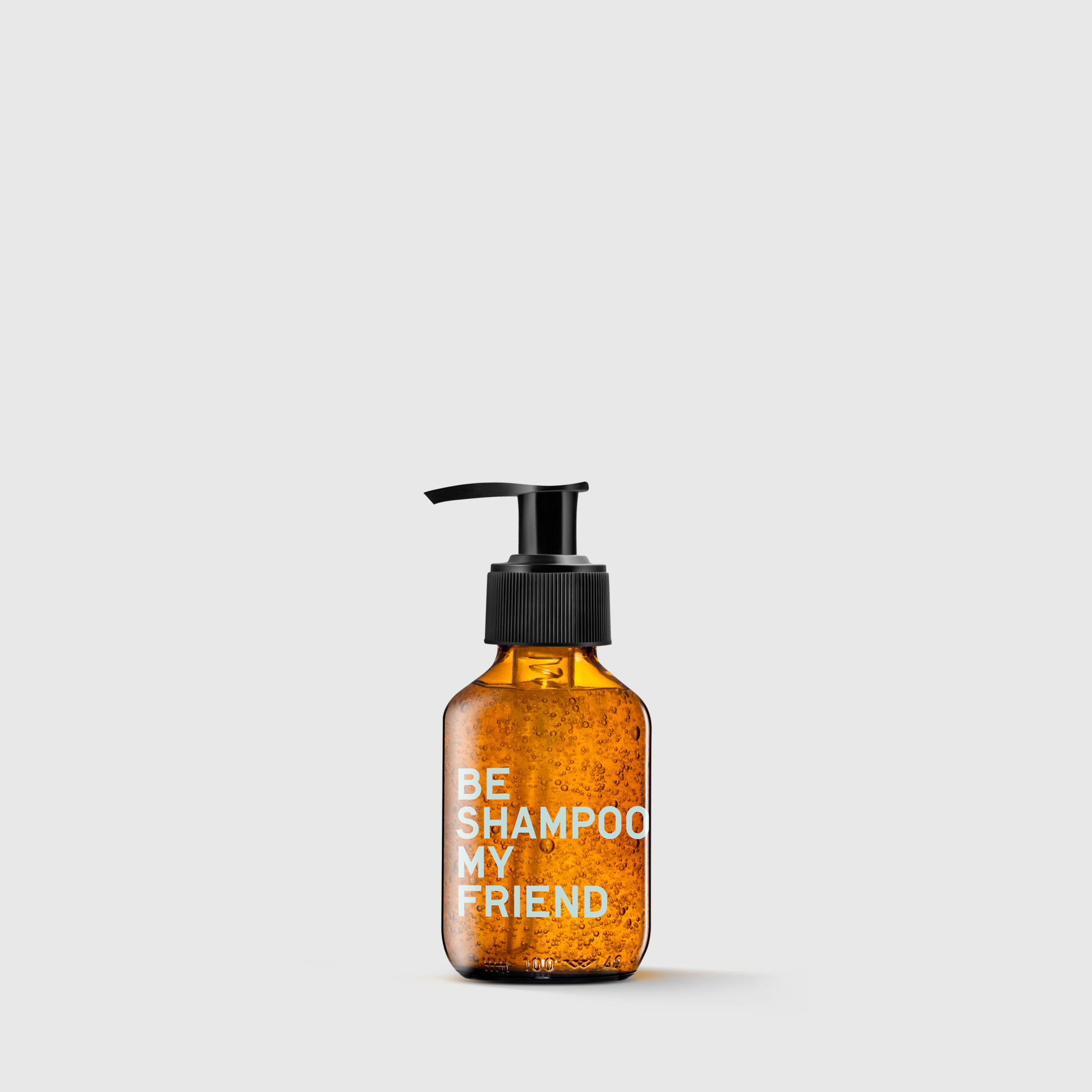 Amber pump bottle labeled "BE SHAMPOO MY FRIEND" with visible bubbles inside.