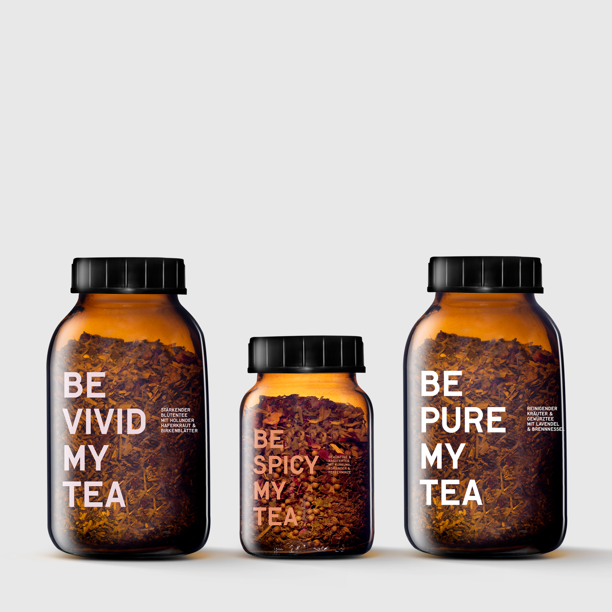 Three amber glass tea jars with black lids labeled Be Vivid My Tea, Be Spicy My Tea, and Be Pure My Tea.