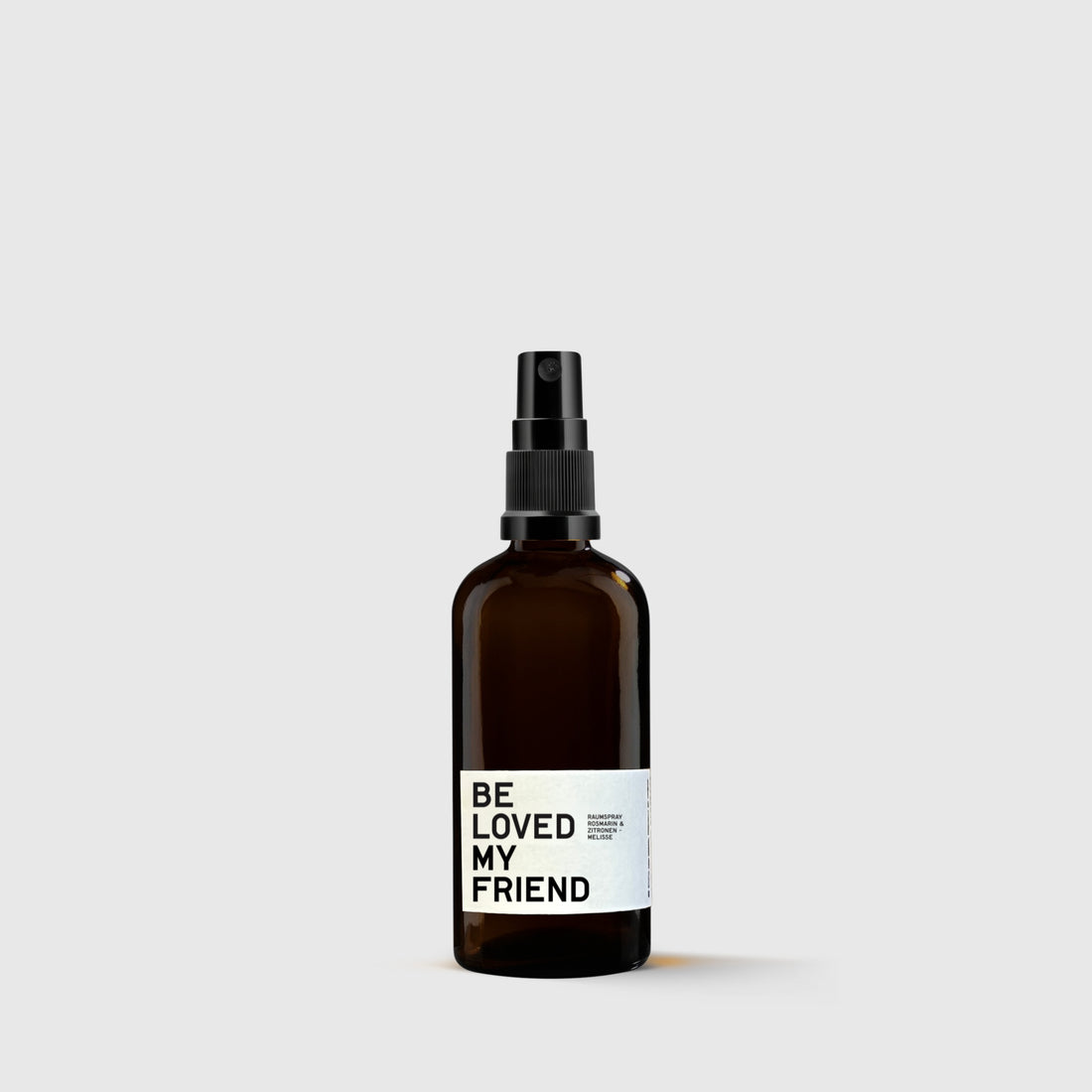 Brown glass spray bottle with black sprayer and white label reading &quot;Be Loved My Friend&quot;.