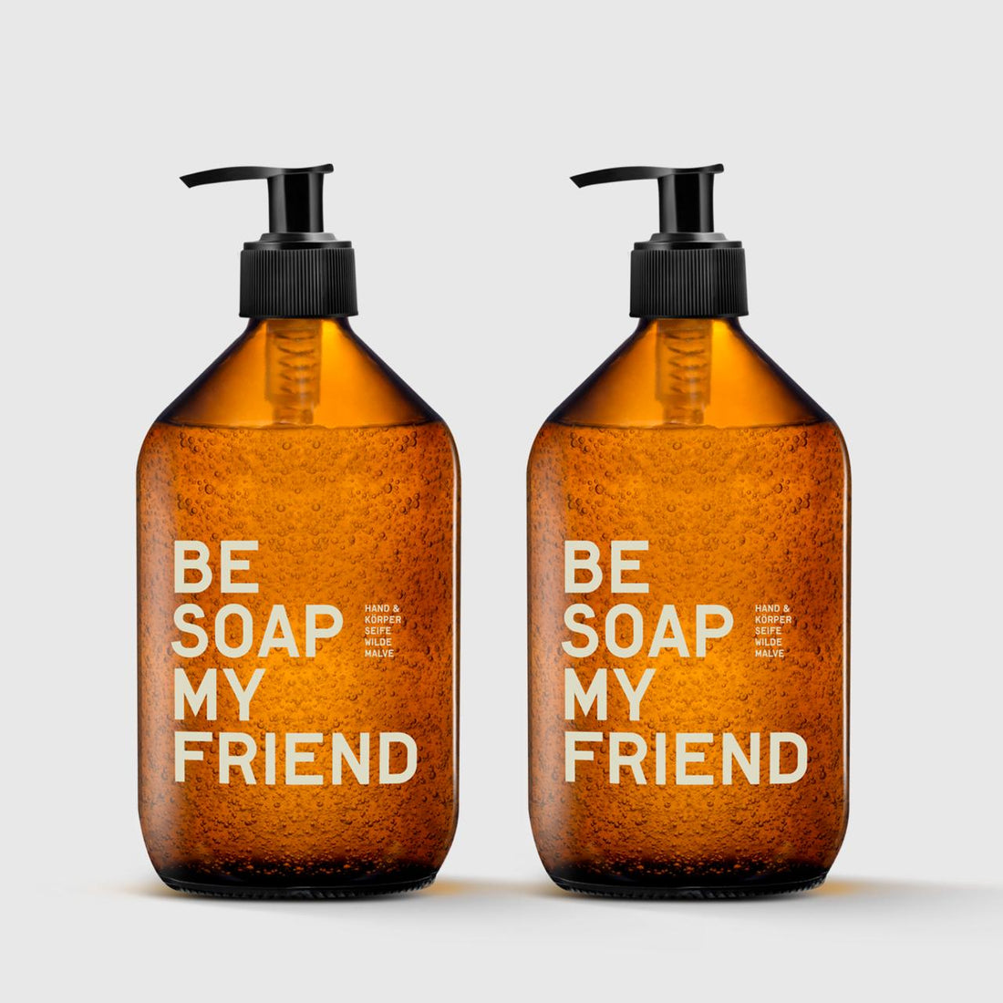 Two amber glass pump bottles labeled &quot;BE SOAP MY FRIEND&quot; with black dispensers against a gray background.