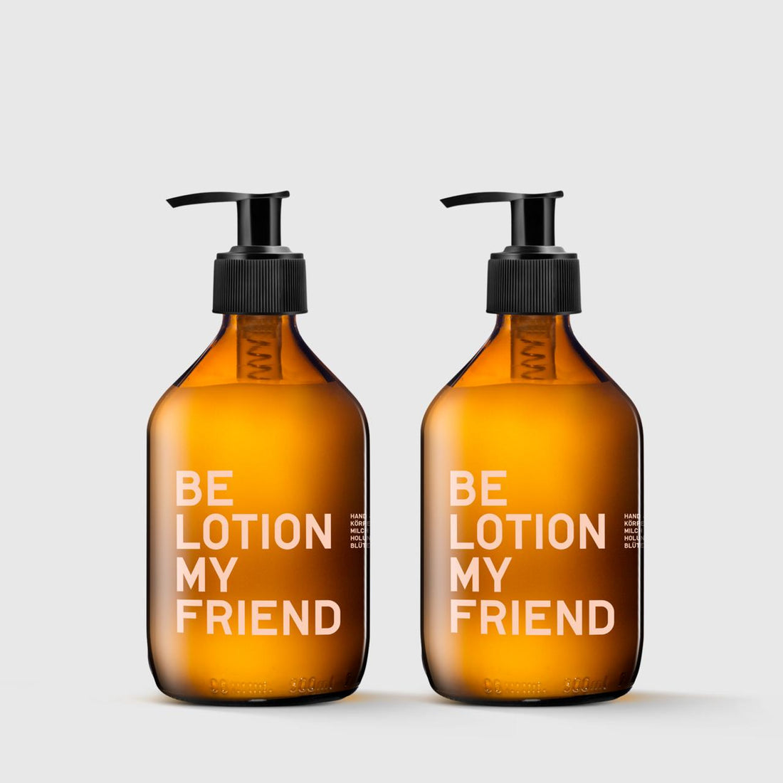 Two amber glass pump bottles labeled &quot;BE LOTION MY FRIEND&quot; with black dispensers on a light gray background.