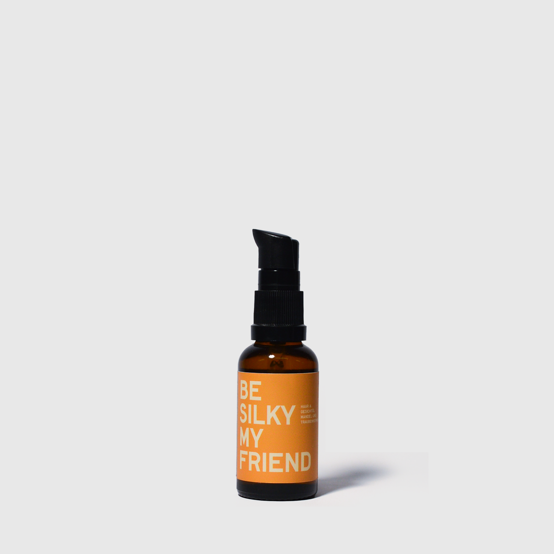 30ml amber glass bottle of almond hair oil with black pump and orange label reading "Be Silky My Friend".